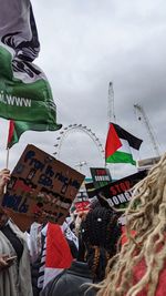 Low angle view of people with flag against sky