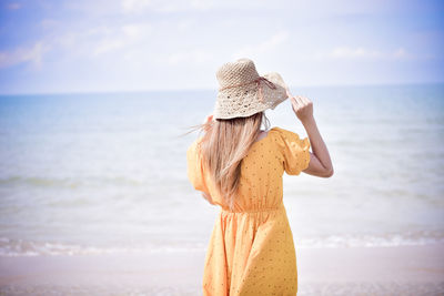 Rear view of woman wearing hat looking at sea against sky
