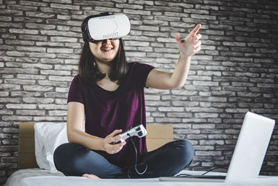 Woman wearing 3-d glasses while sitting on bed at home