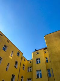 Low angle view of yellow building against blue sky