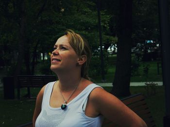 Close-up of smiling mid adult woman looking away against trees