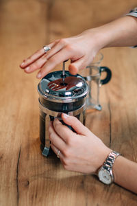 Cropped hands of woman holding coffee maker