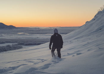 Man walking on snowy land during sunset