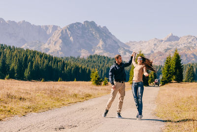 Cheerful couple standing on road against mountains
