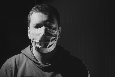 Close-up portrait of man with mask against black background