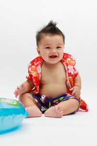 Portrait of cute boy sitting against white background