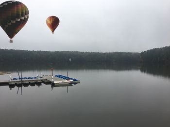 Hot air balloons in lake against sky