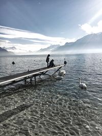 People on lake against sky