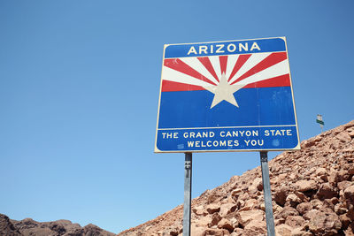 Information sign on rocks against clear blue sky