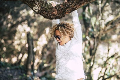 Woman standing by tree trunk