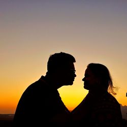 Silhouette man and woman against sky during sunset