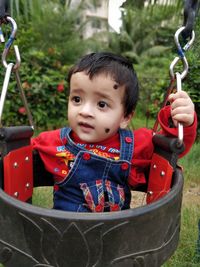 Cute girl looking away while sitting in swing at playground