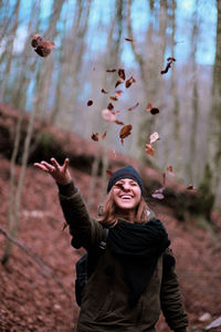 Portrait of young happy girl throws leaves in the air