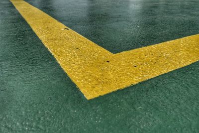 High angle view of yellow arrow symbol on wet road