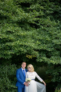 Portrait of bridal couple standing against tree branches at park