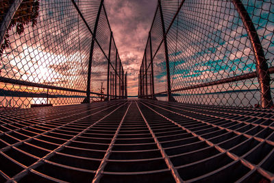 Chainlink fence against sky during sunset