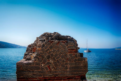 Rocks in front of sea against clear blue sky