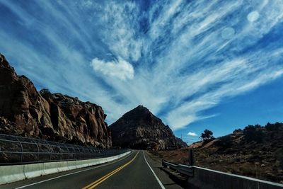 Road by mountains against sky