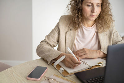 Young woman using laptop while sitting on table