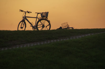 Bicycle on field against sky during sunset