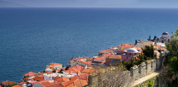 Buildings by sea on sunny day