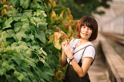 Portrait of smiling woman standing against plants