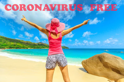 Full length of woman standing at beach against sky