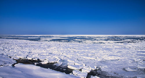 Scenic view of sea against clear blue sky during winter