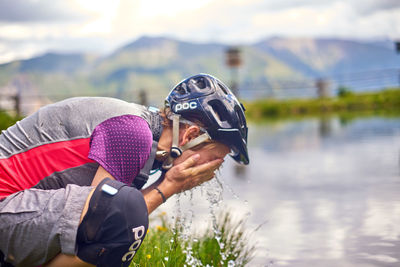 Rear view of man with umbrella on lake