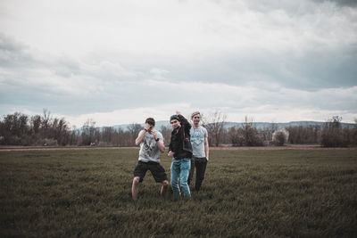 Full length of friends standing on field against sky