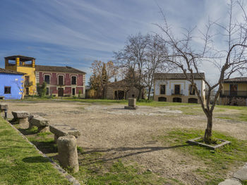 Houses on field by buildings against sky