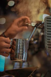 Cropped hands of barista making coffee in cafe