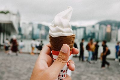 Midsection of woman holding ice cream in city