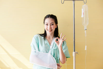 Portrait of a smiling young woman standing against wall