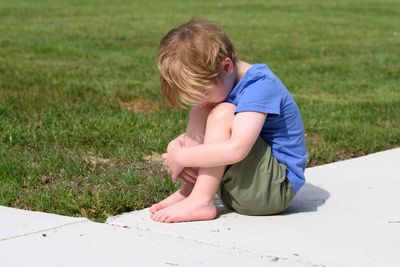 Side view of boy sitting on land