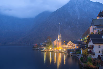 Illuminated buildings by mountains against sky