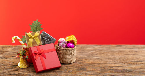 Various flowers in box on table against red wall