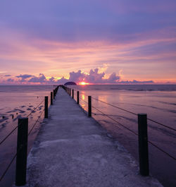 Pier over sea against sky during sunset