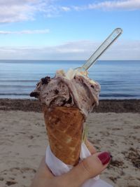 Close-up of hand holding ice cream cone at beach