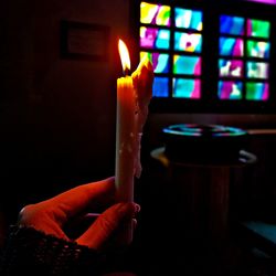 Close-up of hand holding burning candle