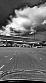 Cars on road against cloudy sky