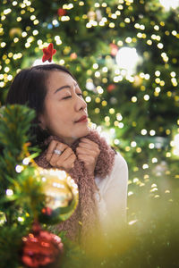 Portrait of young woman standing against christmas tree