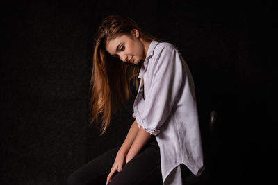 Beautiful young woman standing against black background