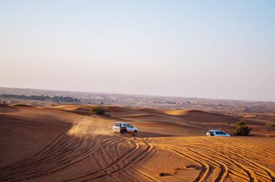 High angle view of off-road vehicles at desert against clear sky