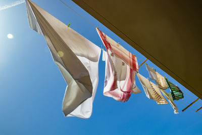 Low angle view of clothes drying against clear blue sky