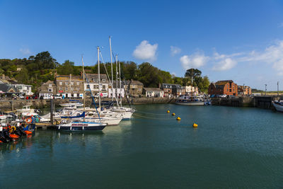 Sailboats moored in harbor against buildings in city