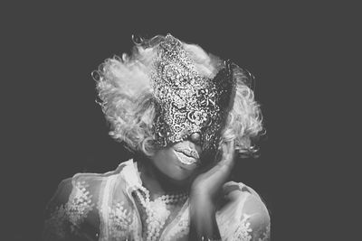 Woman wearing mask against black background