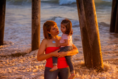 Grandmother carrying granddaughter at beach