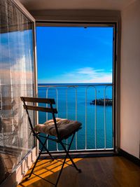 Empty chairs and tables against blue sky seen through window