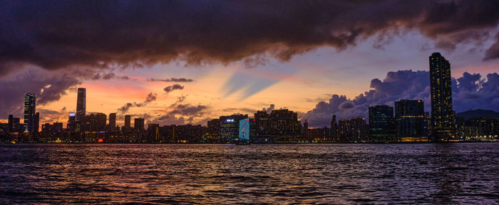 Panoramic view of river and buildings against sky during sunset